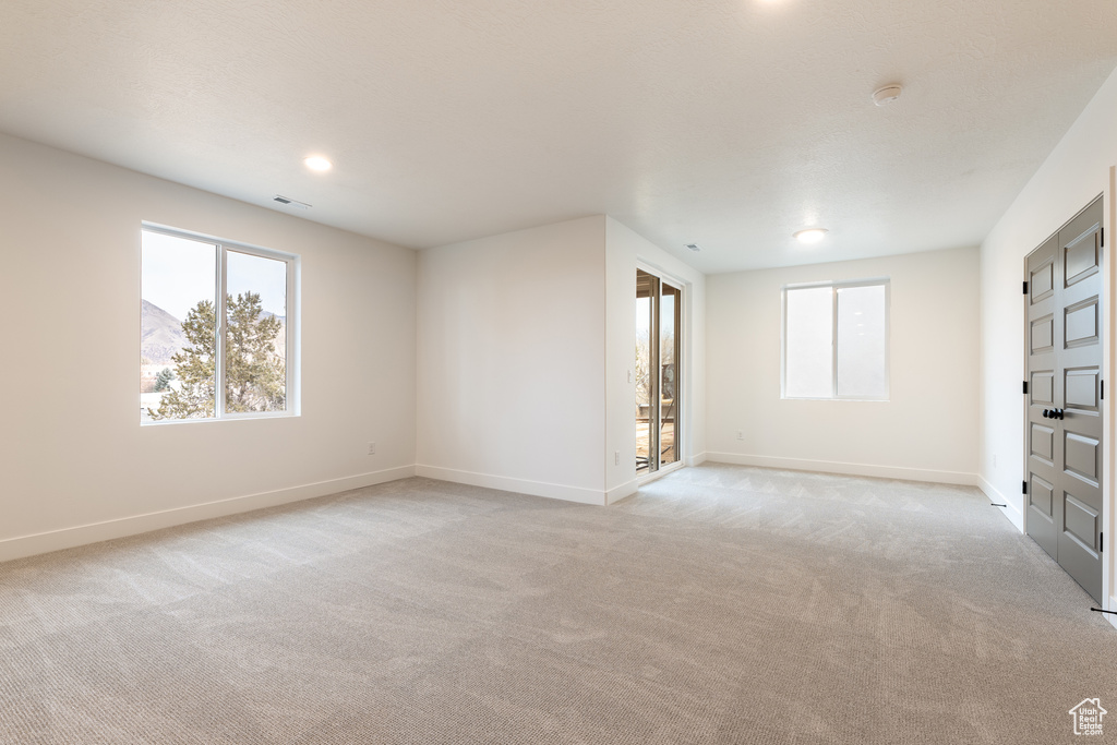 Unfurnished room with recessed lighting, light colored carpet, visible vents, and baseboards