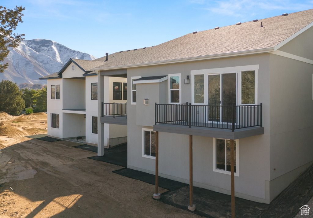 Exterior space with stucco siding, a mountain view, and a balcony