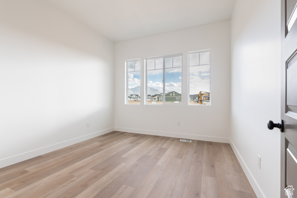 Unfurnished room featuring light wood-style flooring, visible vents, and baseboards