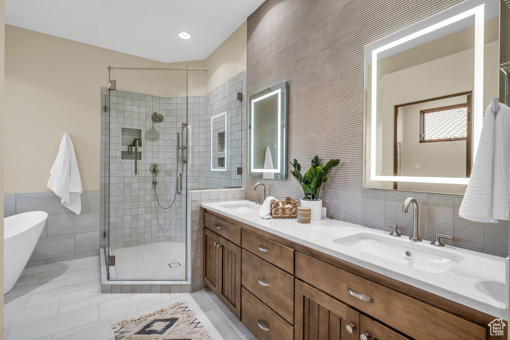 Full bathroom with a sink, tile walls, a stall shower, and double vanity