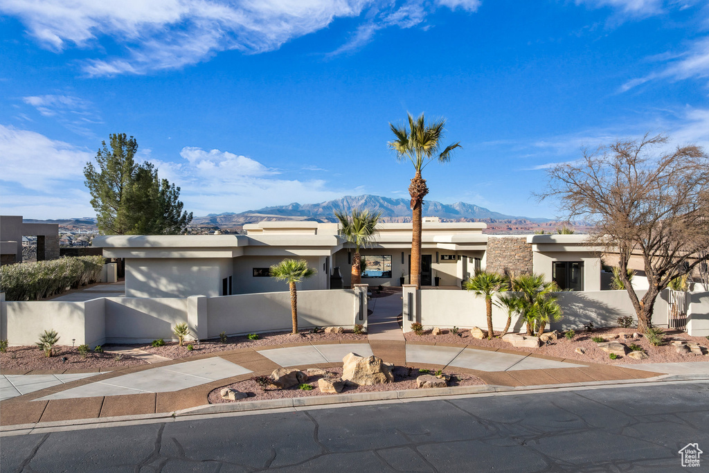 View of front of house featuring a fenced front yard, stucco siding, a mountain view, and a gate