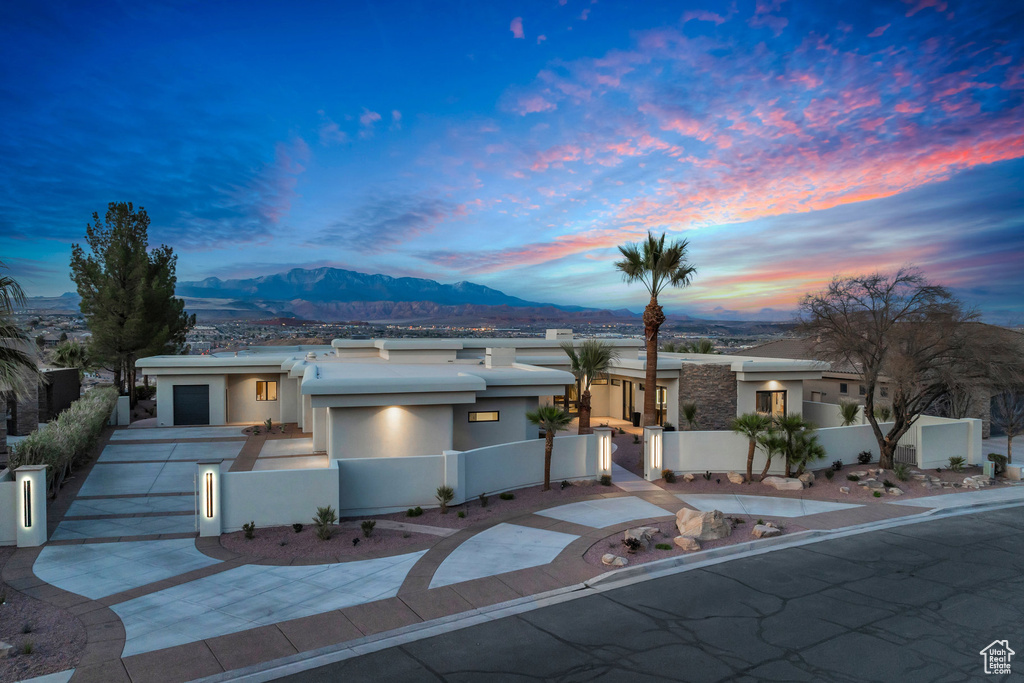 View of front of house with concrete driveway, a mountain view, a fenced front yard, and stucco siding