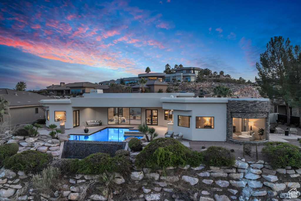 Back of house featuring an outdoor pool, stucco siding, and a patio area