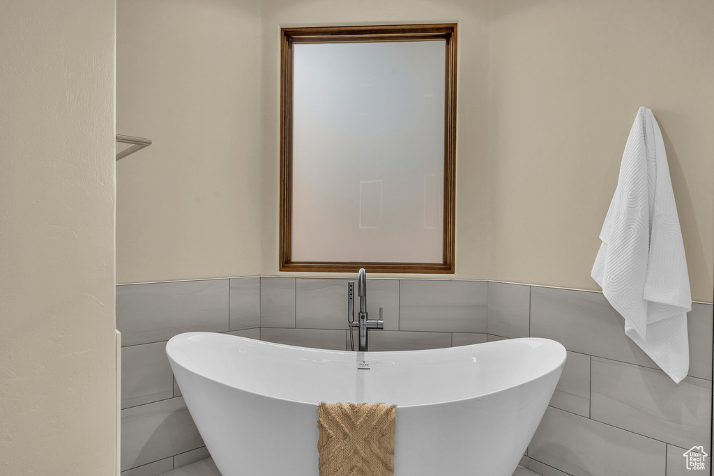 Full bathroom with a sink, a freestanding bath, and wainscoting