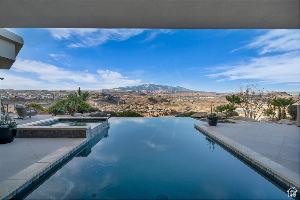 View of pool with a patio, a mountain view, and a pool with connected hot tub