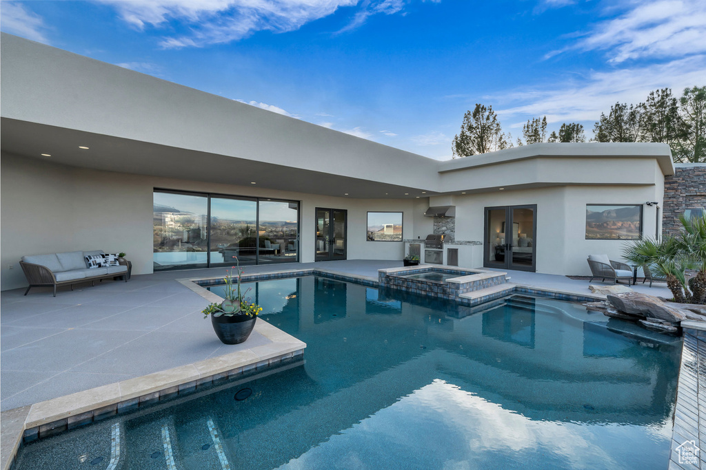 View of swimming pool with french doors, a patio, exterior kitchen, and a pool with connected hot tub