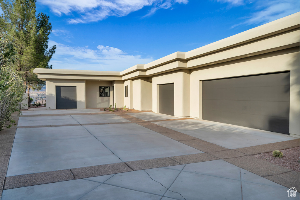 View of front of property featuring stucco siding, a garage, and driveway