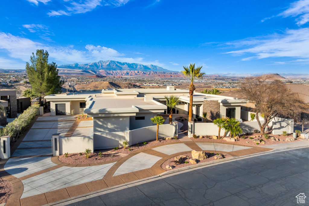 View of front facade with a fenced front yard, stucco siding, driveway, a mountain view, and a gate
