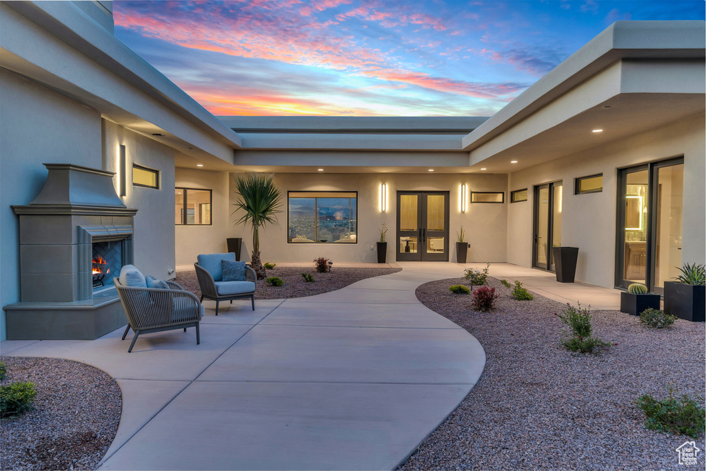 Patio terrace at dusk with french doors and a warm lit fireplace