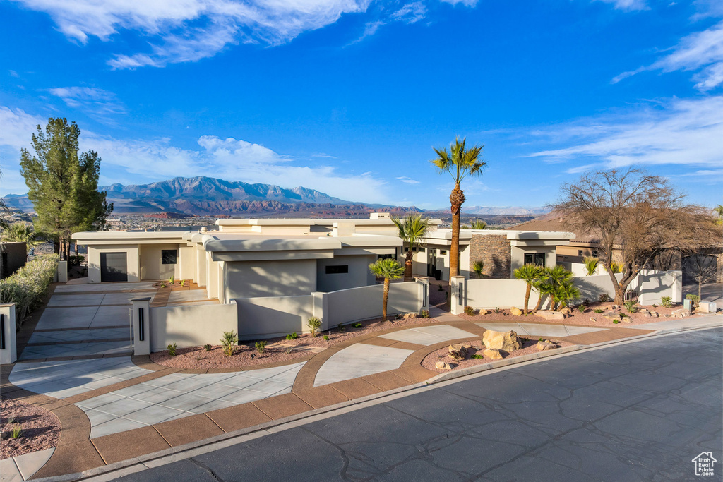 View of front of house with stucco siding, a fenced front yard, a mountain view, and a gate