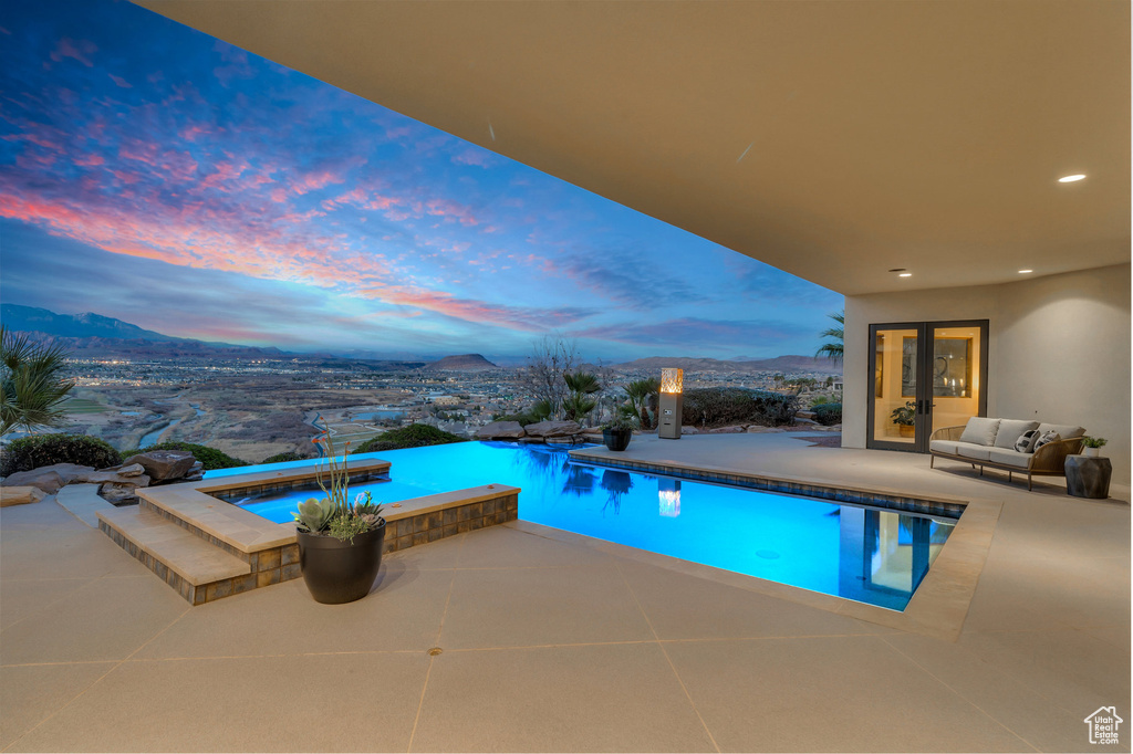 Pool at dusk with a mountain view, a patio, and an infinity pool