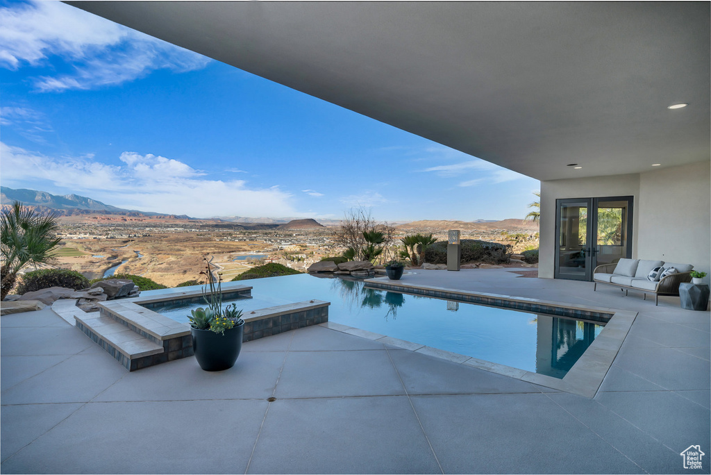 Outdoor pool with a mountain view, a patio, and an in ground hot tub