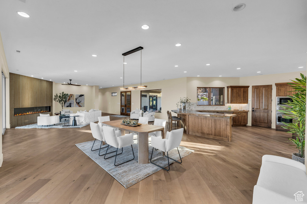 Dining space with a large fireplace, recessed lighting, and light wood-style flooring