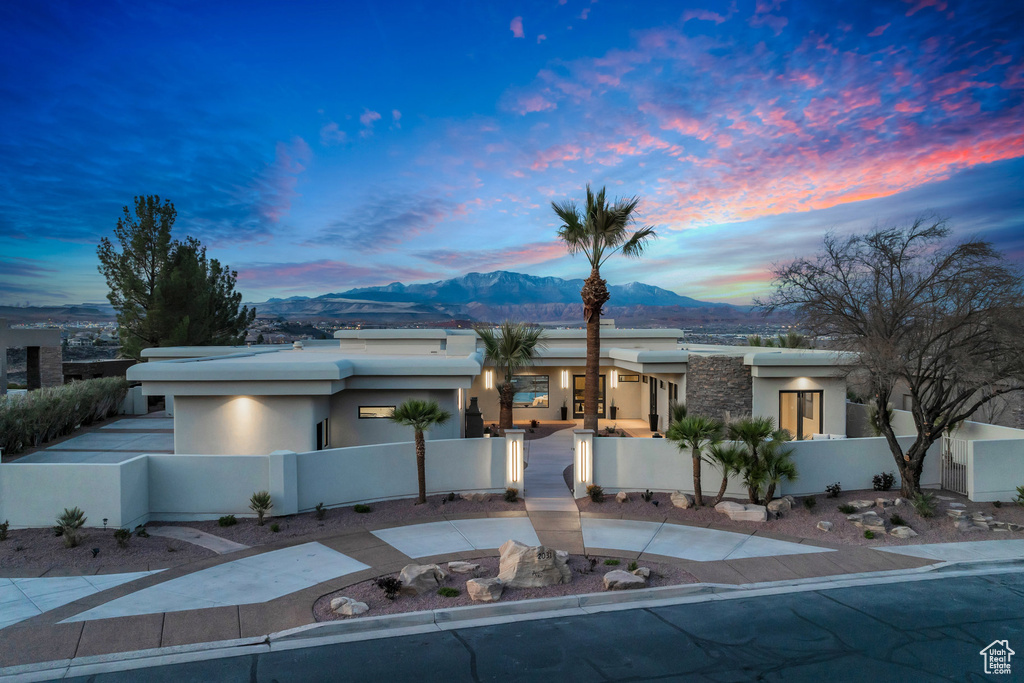 View of front facade featuring a fenced front yard, stucco siding, driveway, a mountain view, and a gate