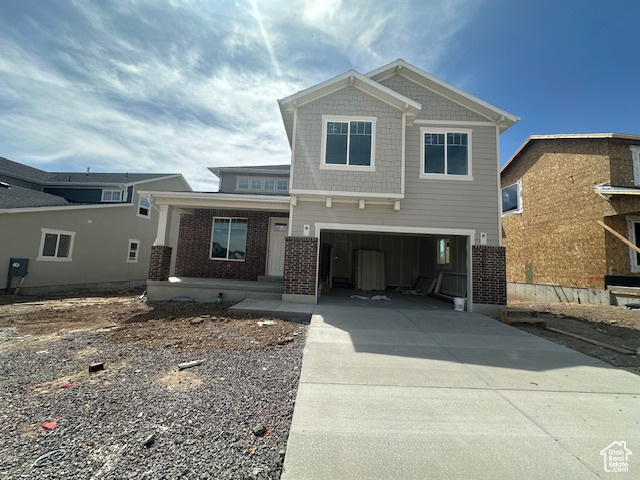 Craftsman inspired home with a porch, an attached garage, driveway, and brick siding