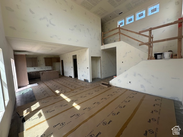 Unfurnished living room featuring a towering ceiling