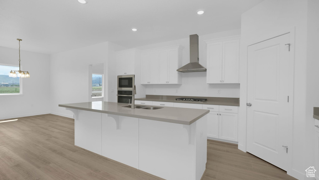 Kitchen featuring wall chimney exhaust hood, a sink, appliances with stainless steel finishes, plenty of natural light, and recessed lighting