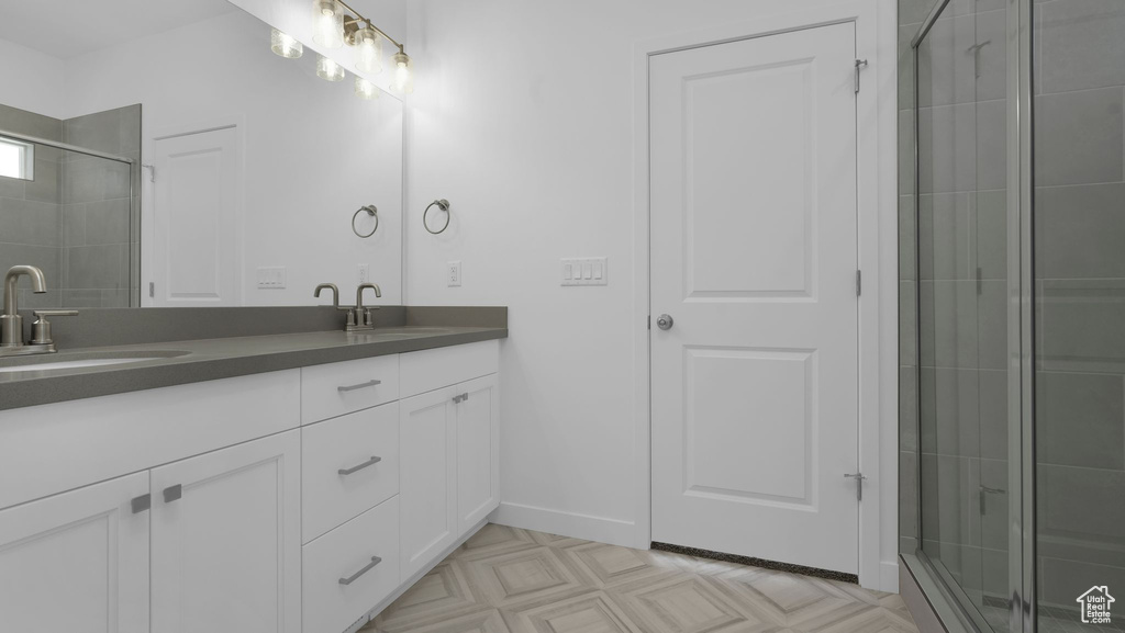 Full bathroom featuring double vanity, tiled shower, and baseboards