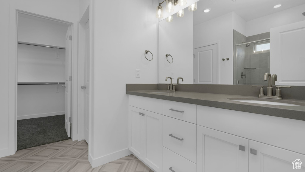 Bathroom with double vanity, a stall shower, a walk in closet, baseboards, and recessed lighting