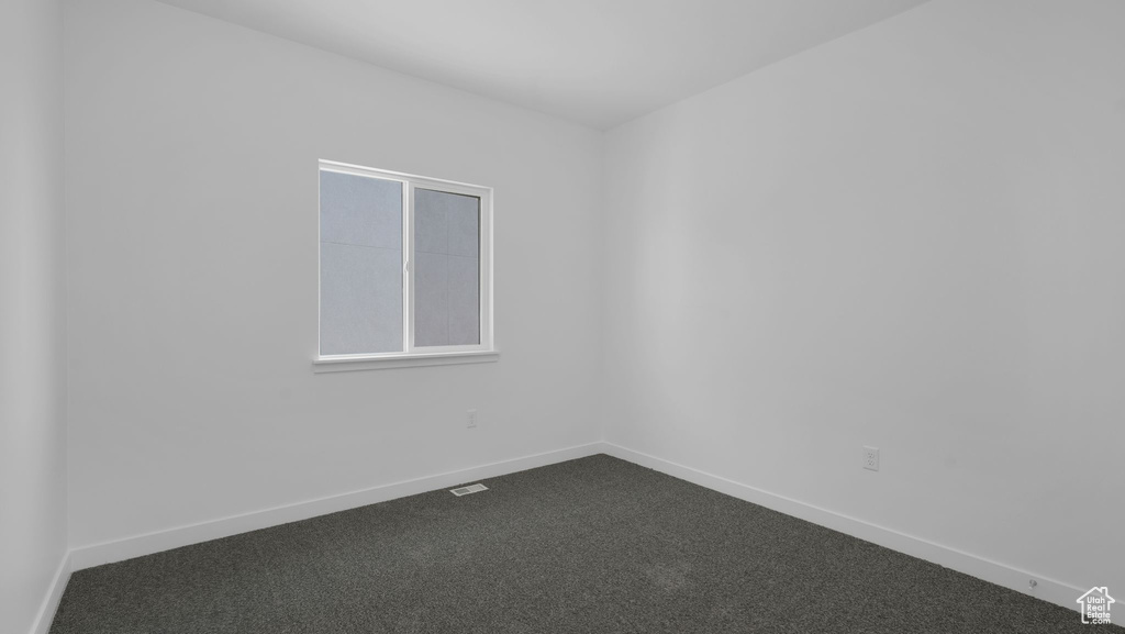 Unfurnished room with dark carpet and baseboards