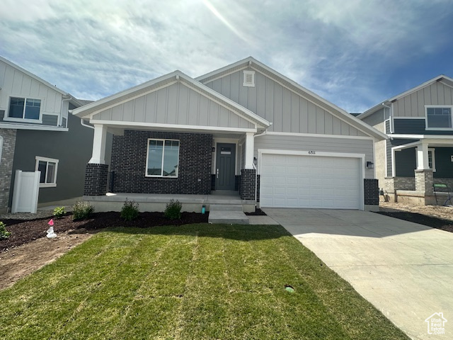 Craftsman inspired home with board and batten siding, driveway, a garage, brick siding, and a front lawn