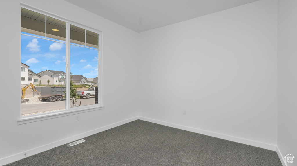 Carpeted empty room featuring baseboards and a residential view