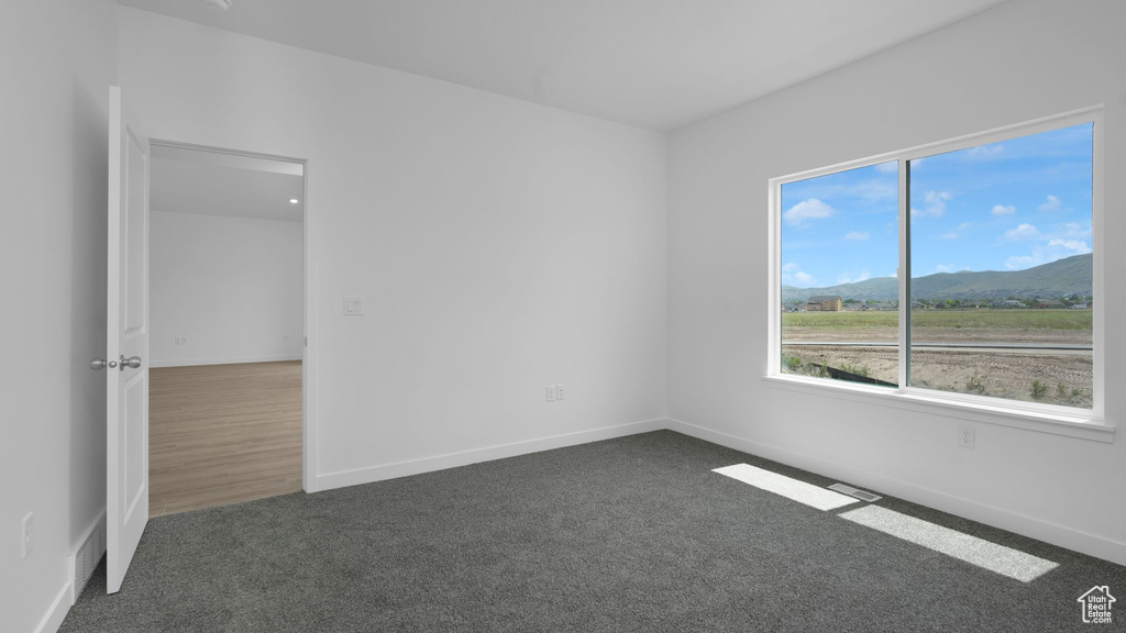 Unfurnished room with dark carpet, a mountain view, and baseboards