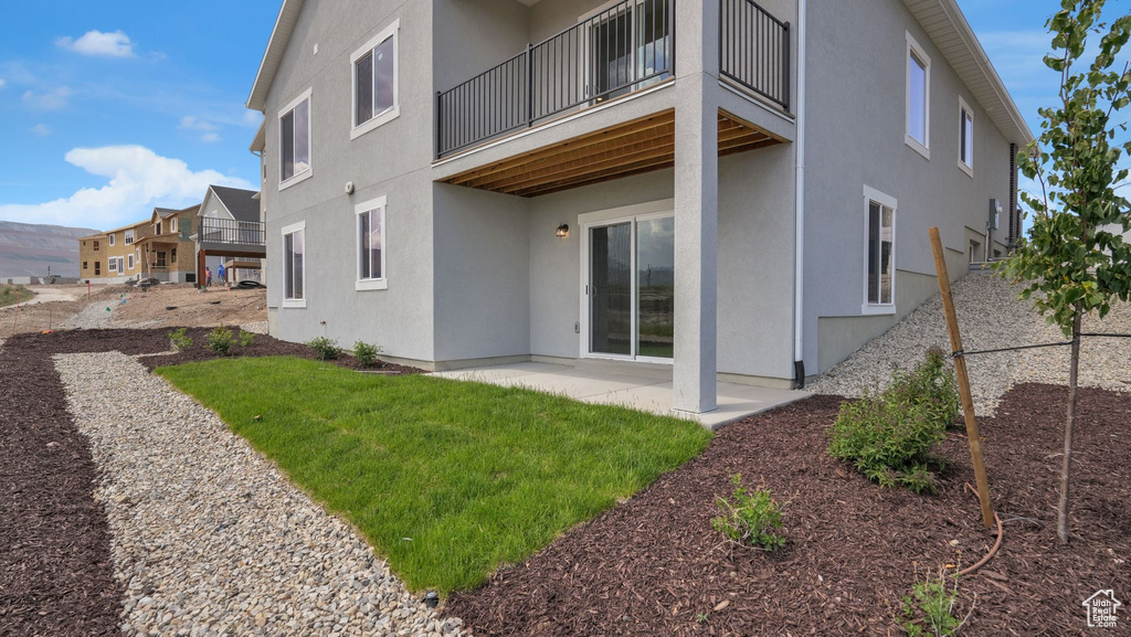 Rear view of property featuring stucco siding, a balcony, and a patio area
