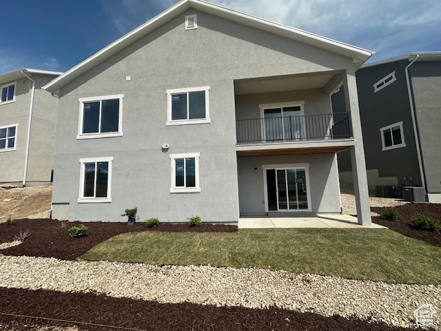 Rear view of house with a yard, a patio area, stucco siding, and a balcony