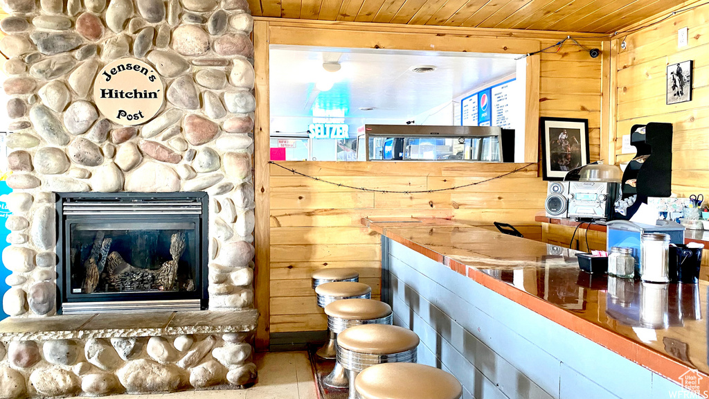 Interior space featuring a stone fireplace, wood ceiling, and wood walls