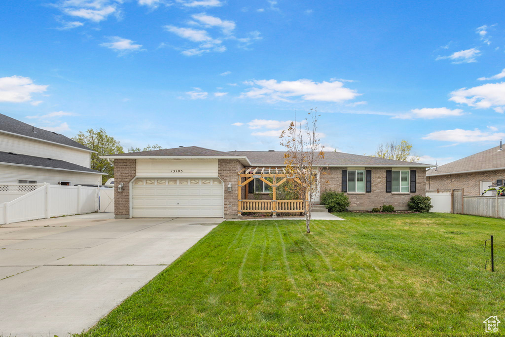 Single story home featuring fence, an attached garage, a front lawn, brick siding, and concrete driveway