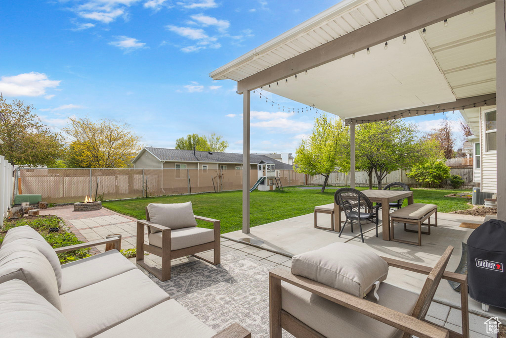 View of patio / terrace with a fenced backyard, an outdoor living space with a fire pit, a playground, and outdoor dining space