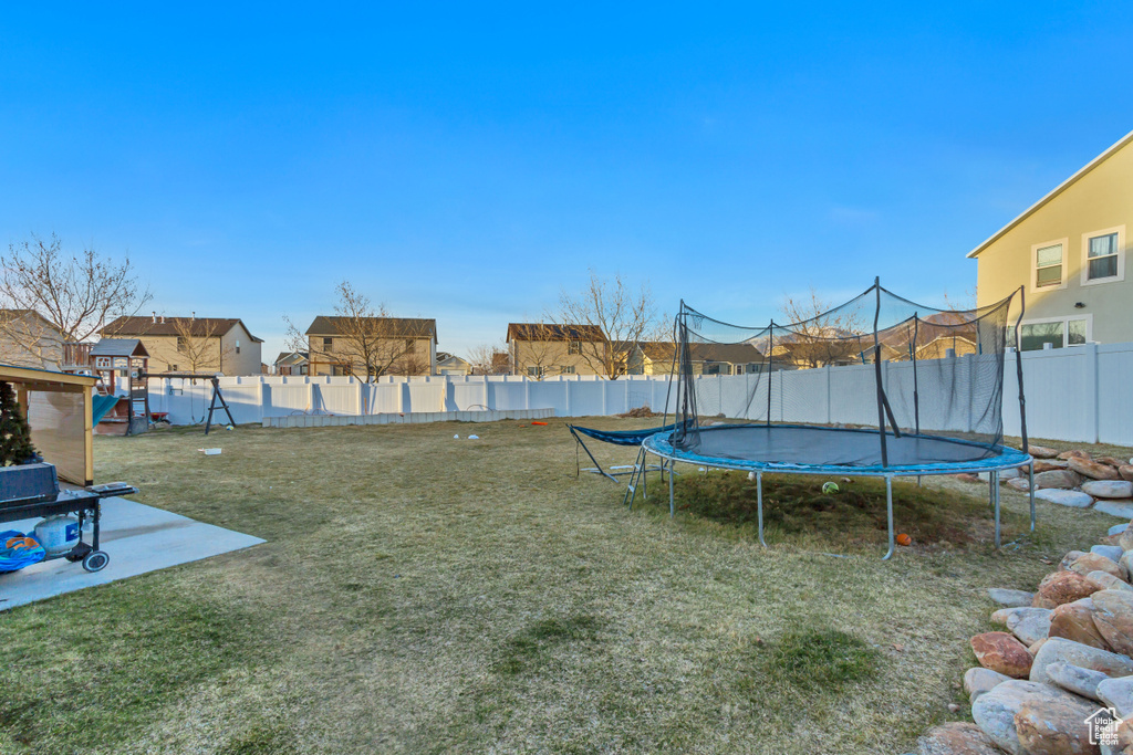 View of yard featuring a fenced backyard, a patio, a playground, and a trampoline