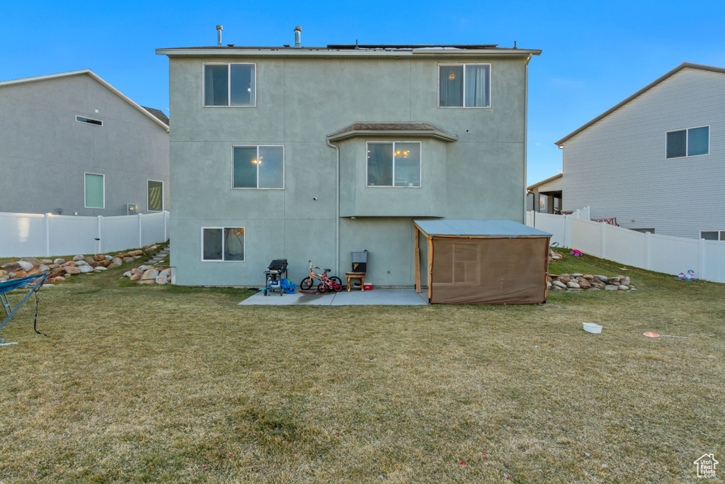 Rear view of property with stucco siding, a patio, a lawn, and a fenced backyard
