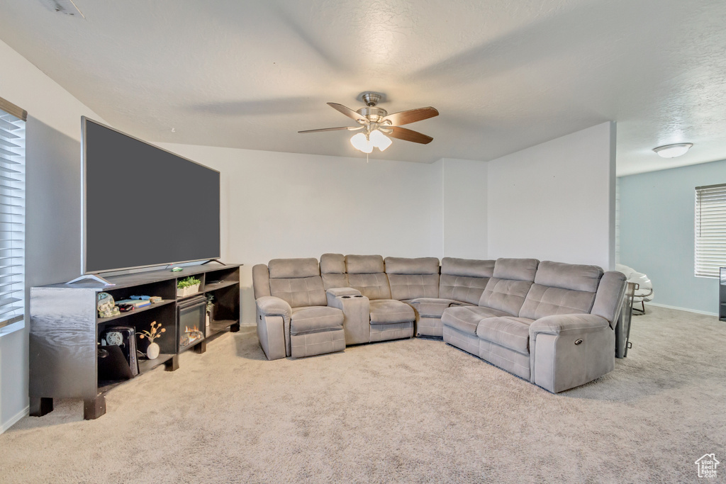 Carpeted living room featuring baseboards and ceiling fan