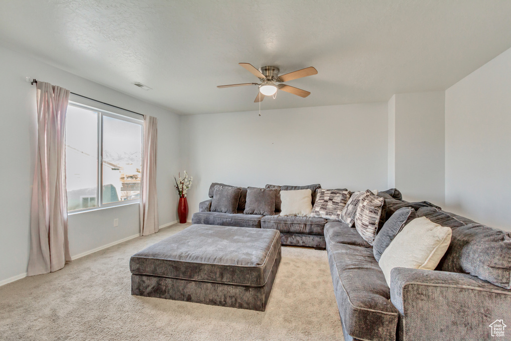 Carpeted living area featuring visible vents, baseboards, and a ceiling fan