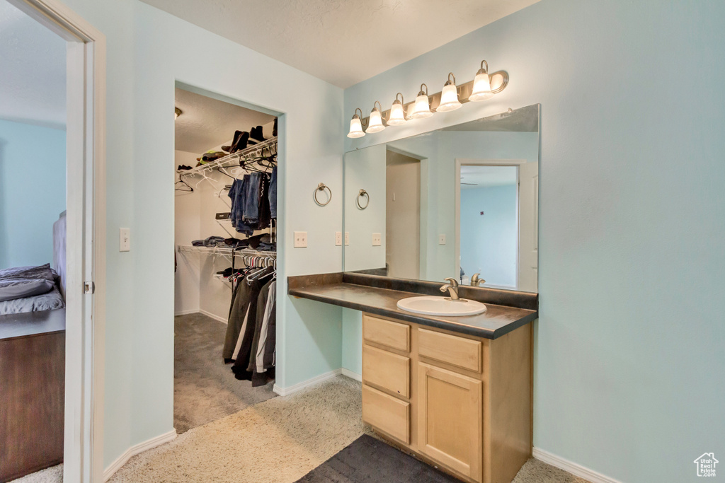 Bathroom with vanity, a walk in closet, and baseboards