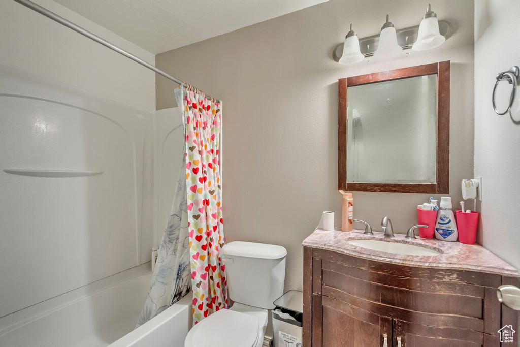 Bathroom with toilet, vanity, and shower / bath combination with curtain
