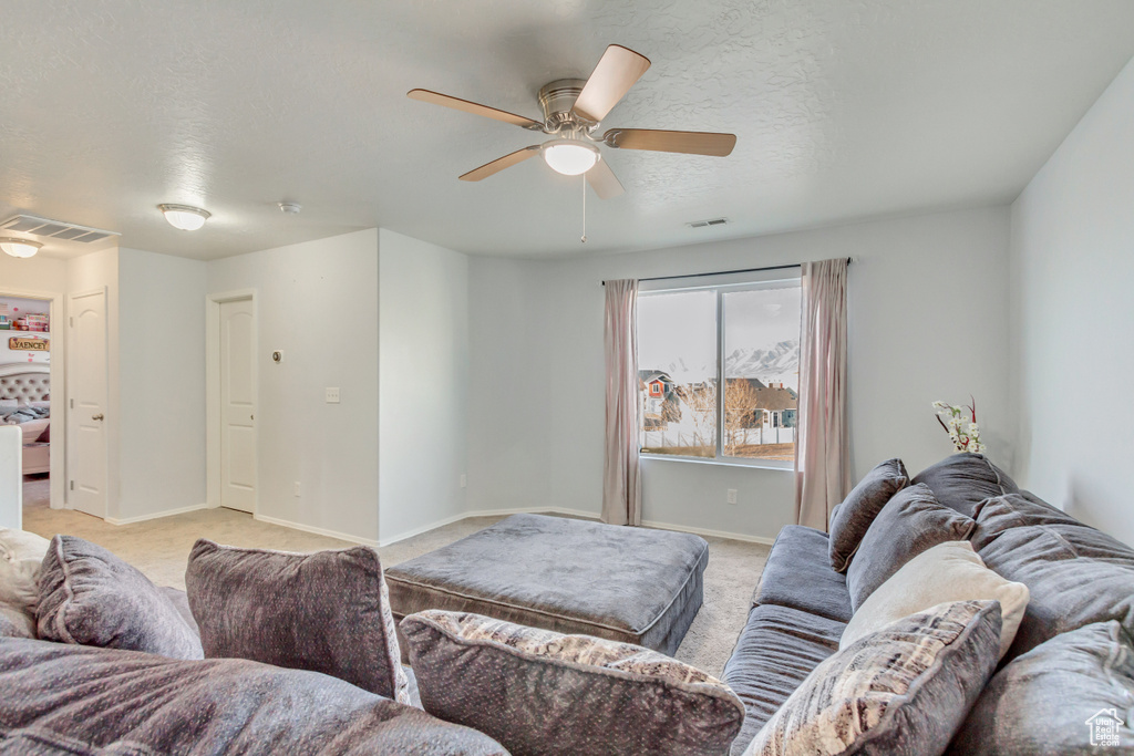 Living room featuring visible vents, light carpet, a textured ceiling, and baseboards