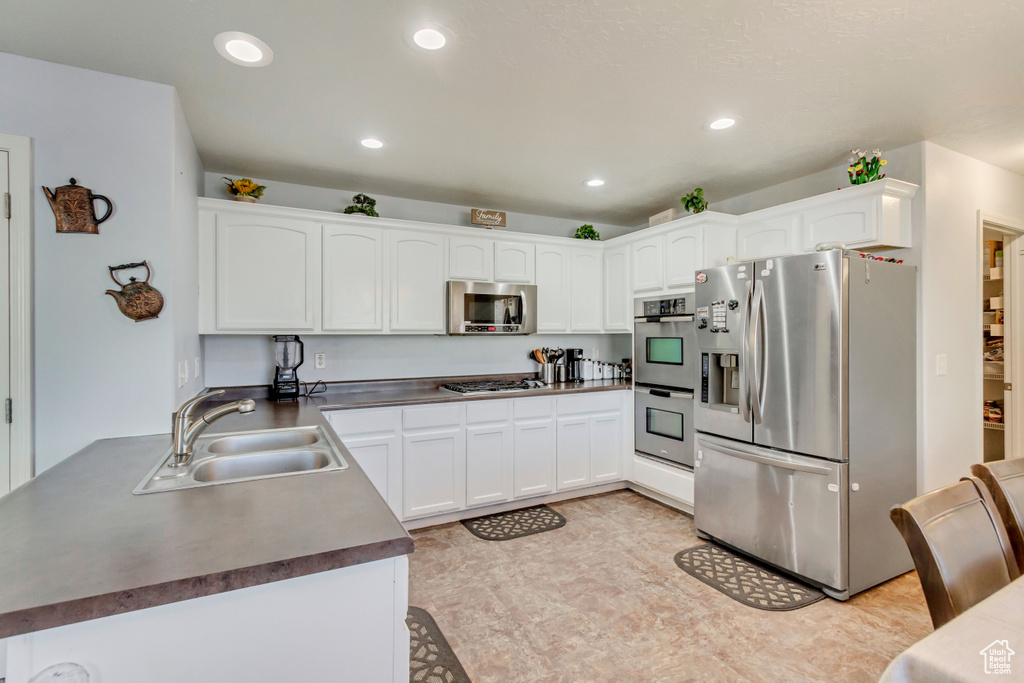 Kitchen featuring a sink, dark countertops, white cabinets, and stainless steel appliances