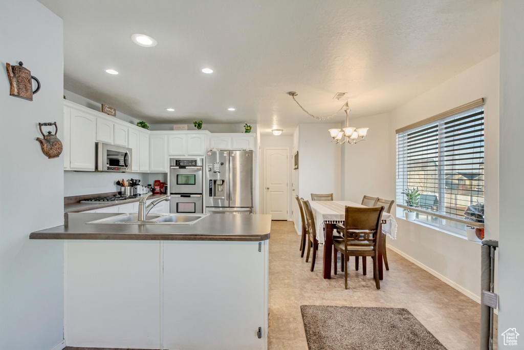 Kitchen featuring a sink, appliances with stainless steel finishes, a peninsula, and white cabinetry