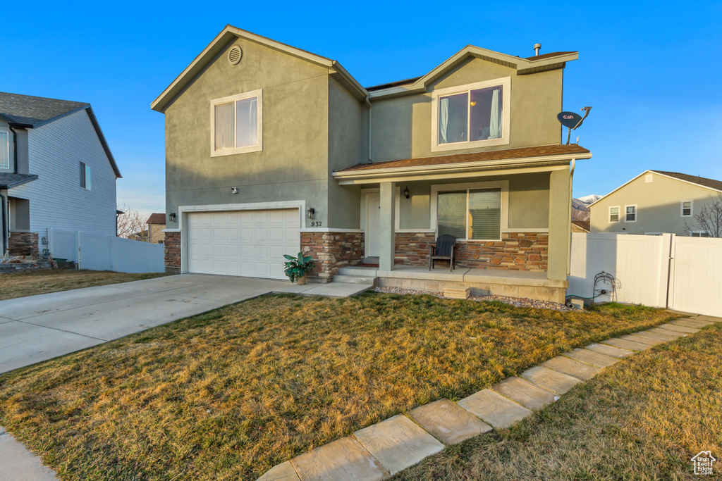 Traditional-style home with stucco siding, covered porch, concrete driveway, and fence