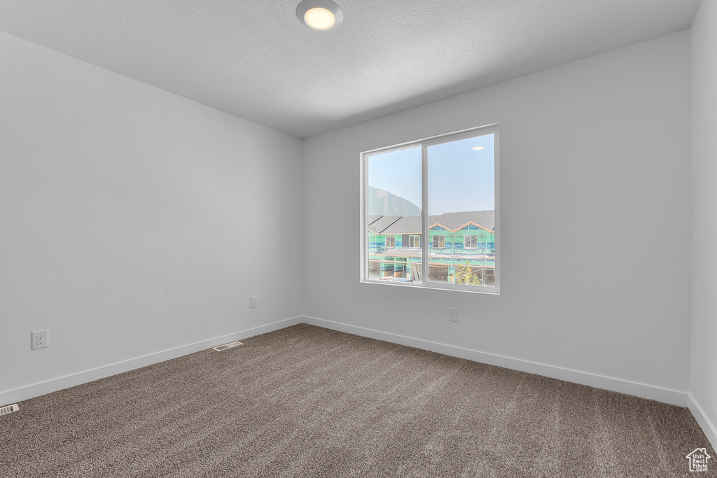 Unfurnished room with baseboards, carpet floors, a textured ceiling, and visible vents
