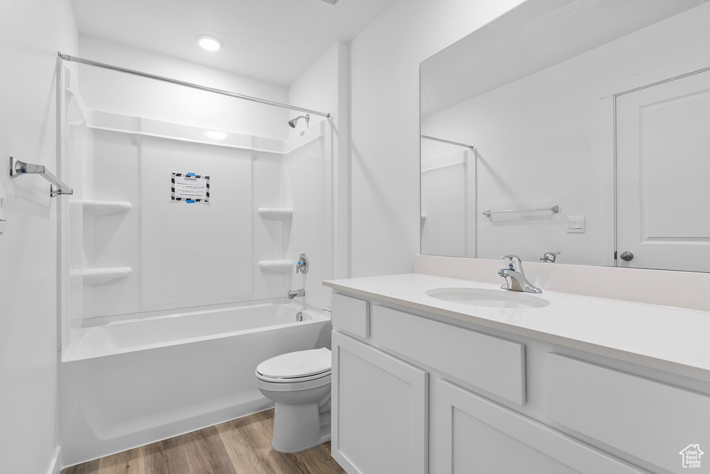 Bathroom featuring shower / bathtub combination, toilet, wood finished floors, and vanity