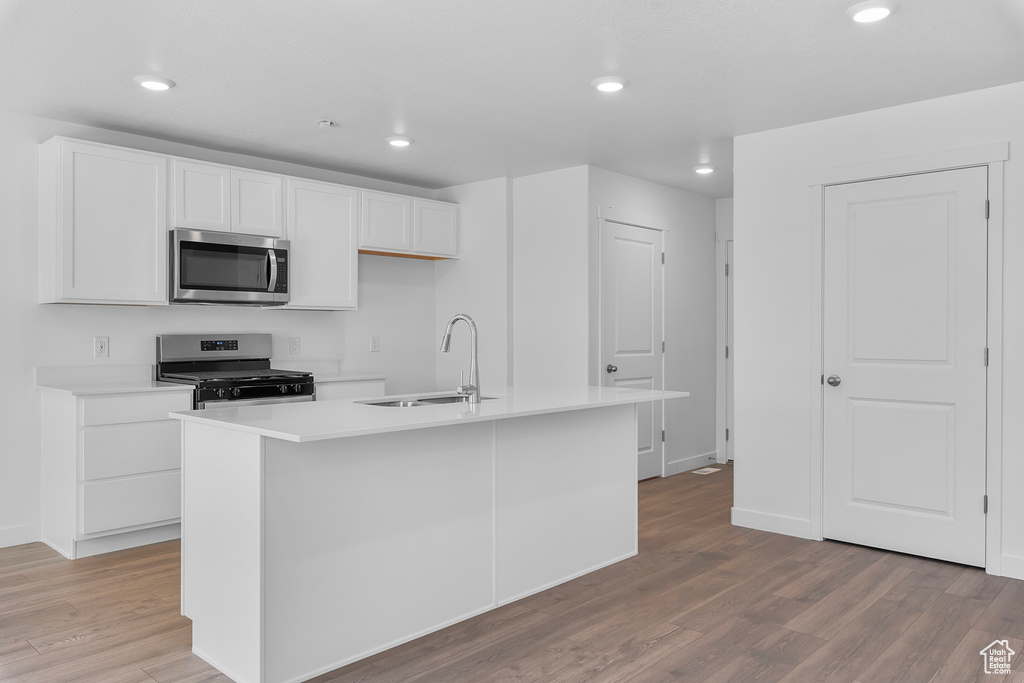 Kitchen with light wood-style flooring, white cabinetry, stainless steel appliances, and a sink