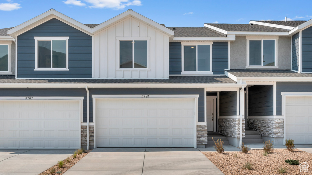 Multi unit property with concrete driveway, a garage, board and batten siding, and stone siding