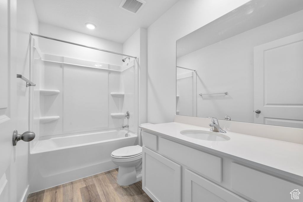 Bathroom featuring vanity, wood finished floors, visible vents, tub / shower combination, and toilet
