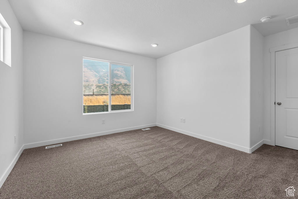 Carpeted spare room featuring visible vents, recessed lighting, and baseboards