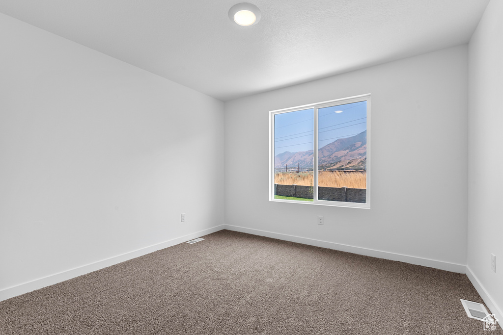 Carpeted empty room with visible vents and baseboards