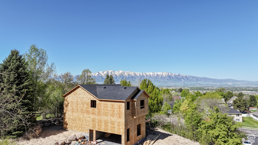 View of side of property featuring a mountain view and roof with shingles